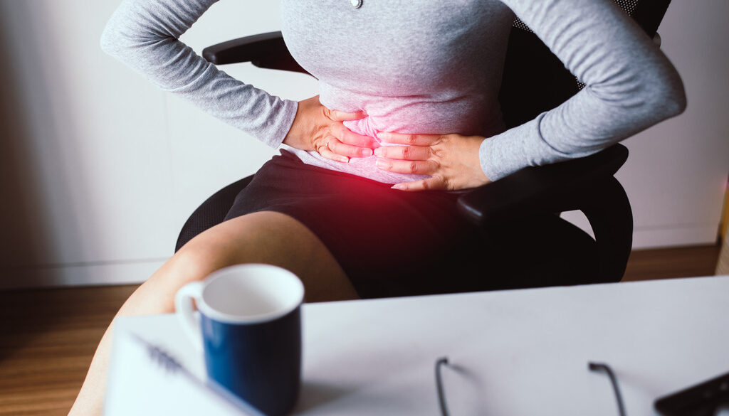 Woman Sitting Holding Her Stomach Dealing With Abdomen Pain What Are the Symptoms of Biliary Disease