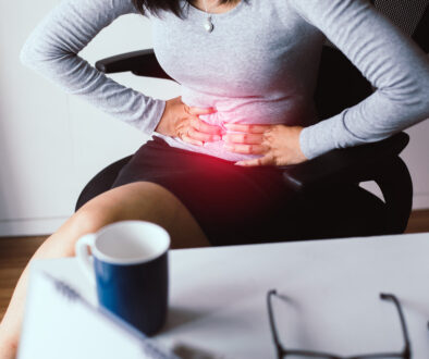 Woman Sitting Holding Her Stomach Dealing With Abdomen Pain What Are the Symptoms of Biliary Disease