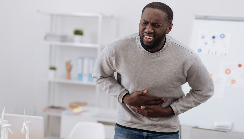 African American Man Standing Holding His Stomach in Pain Ulcerative Colitis Treatment