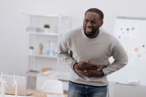 African American Man Standing Holding His Stomach in Pain Ulcerative Colitis Treatment